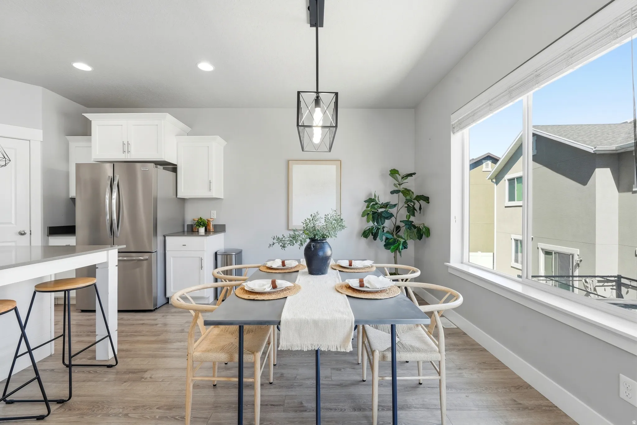Open-concept dining area with wood-finish flooring, a large window, built-in recessed lighting, and a contemporary pendant fixture