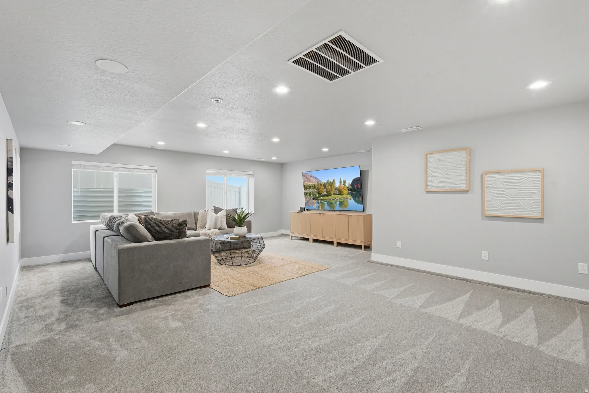 Expansive living area with recessed lighting, light-toned walls, and a large window