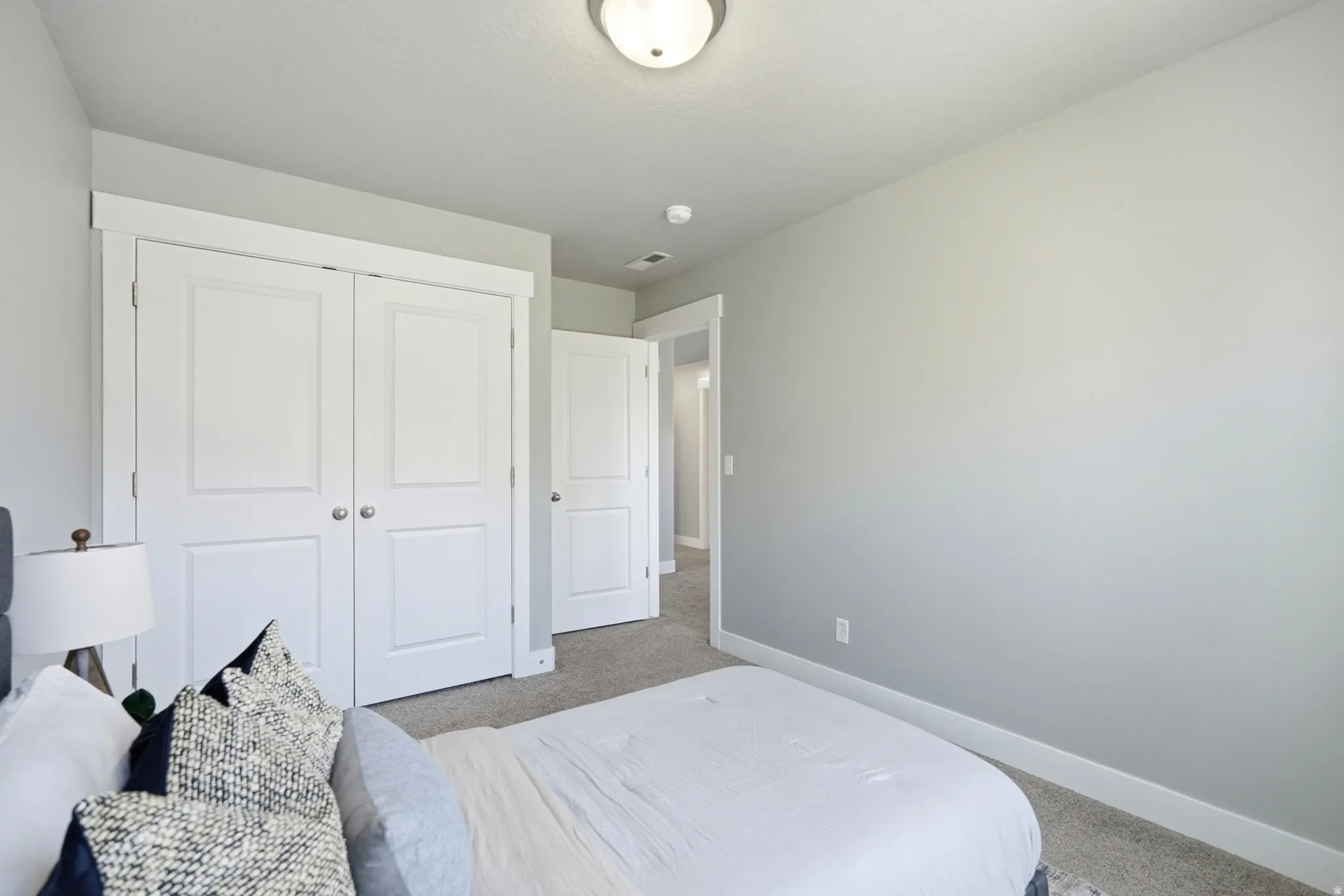 Light gray wall paint, white trim, recessed lighting, white panel doors, and gray carpeting