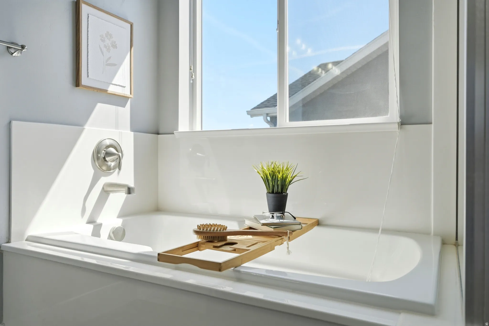 Built-in bathtub with a brushed nickel faucet and bright window