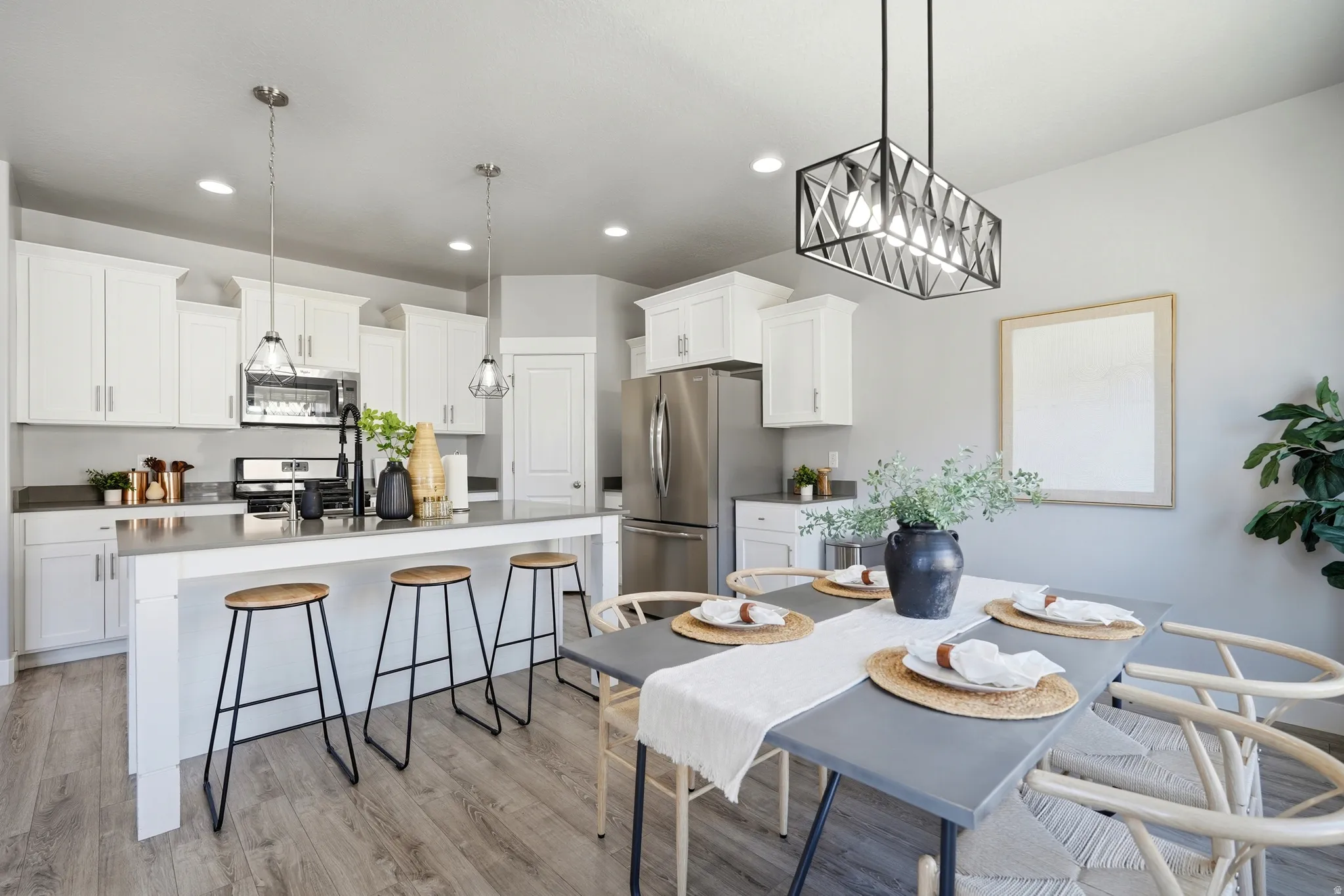 Open-concept kitchen and dining area featuring white cabinetry, stainless steel appliances, wood-finish flooring, and recessed lighting