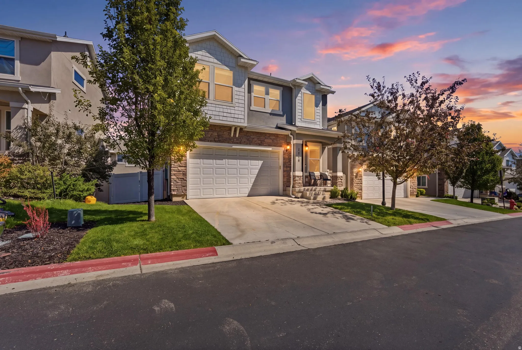 Exterior featuring stone and siding finishes, an attached garage, a concrete driveway, and landscaped front yard