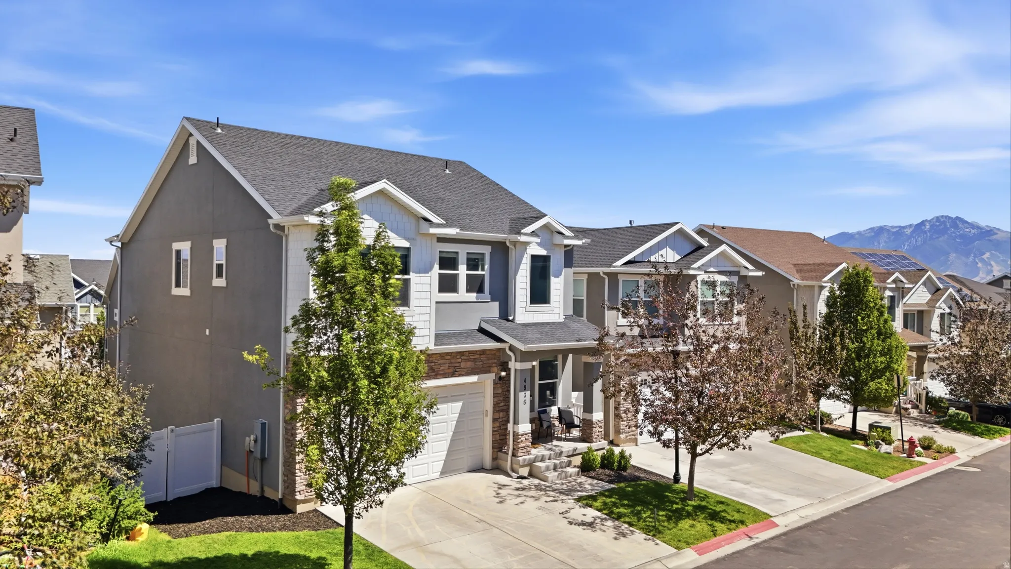 Contemporary residence with a two-car garage, stone and siding facade, and a covered front porch