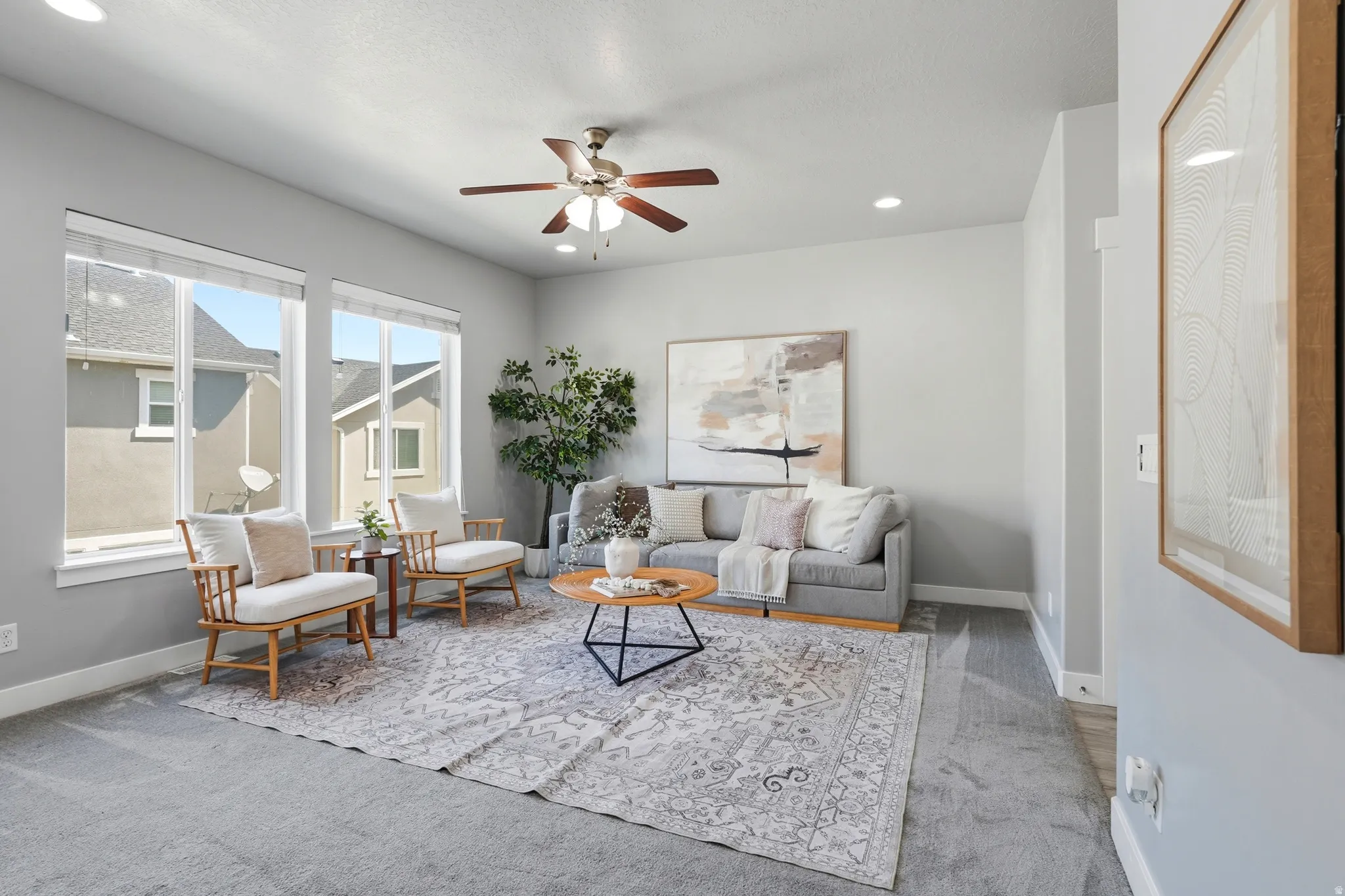 Recessed lighting, ceiling fan, and large windows illuminate this living space