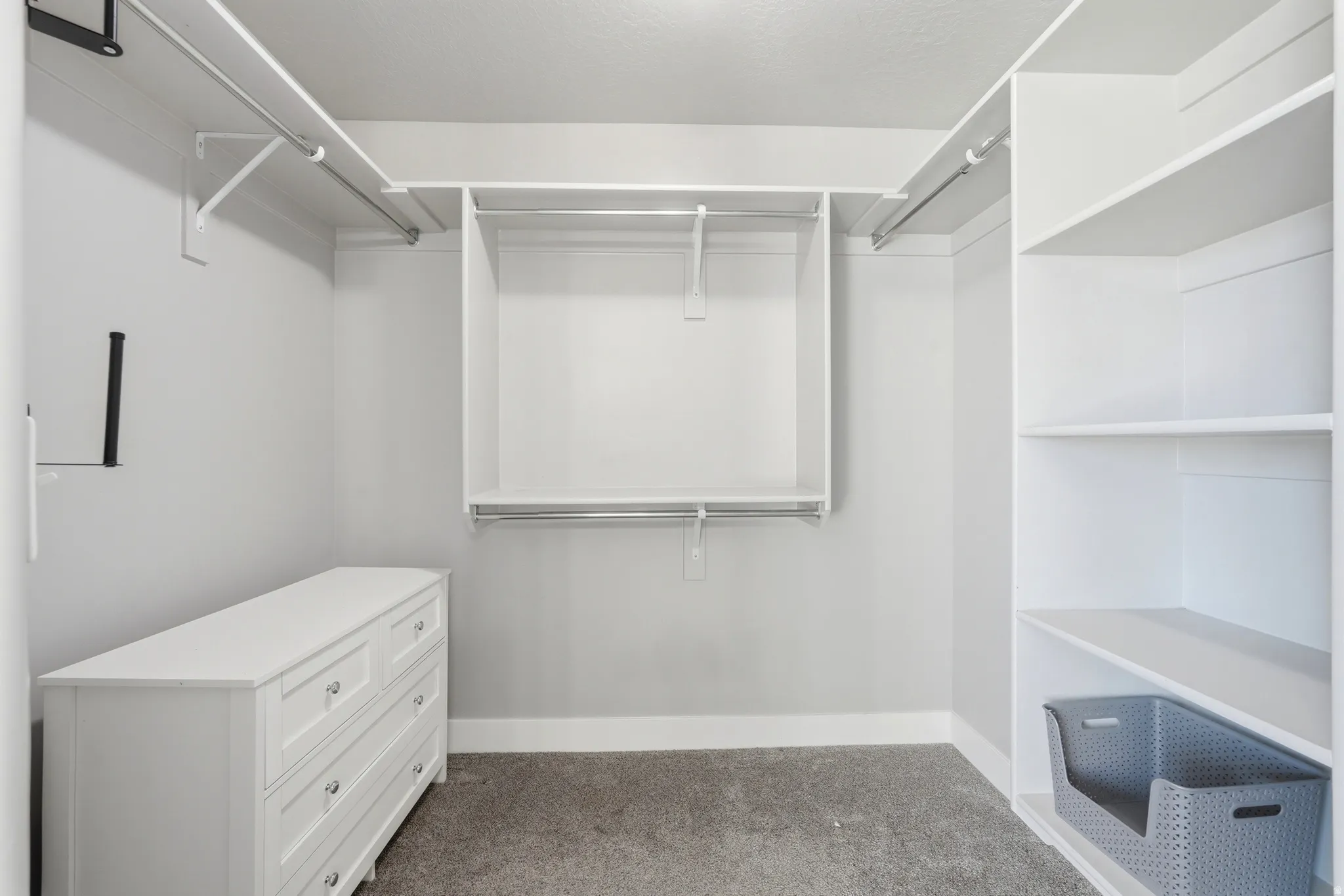 Walk-in closet featuring built-in shelving, hanging rods, and a white dresser with drawers