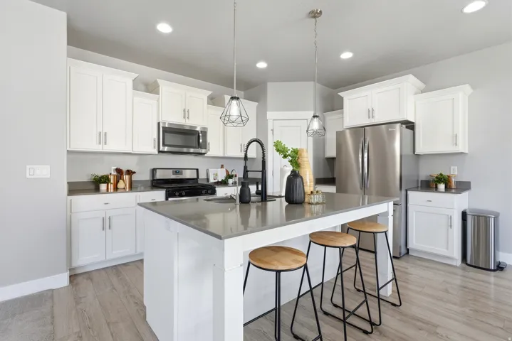 Kitchen featuring white cabinetry, stainless steel appliances, a center island with countertop seating, wood-finish flooring, and recessed lighting