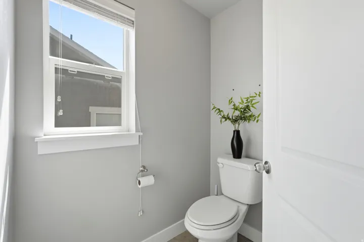Recessed toilet with a white tank and bowl, featuring a single-pane window with white trim