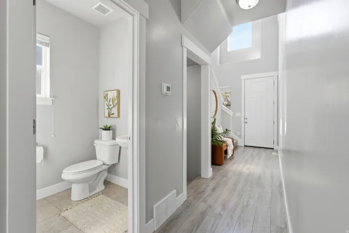Light wood-finish flooring, a white paneled door, high ceilings, and a second-story window