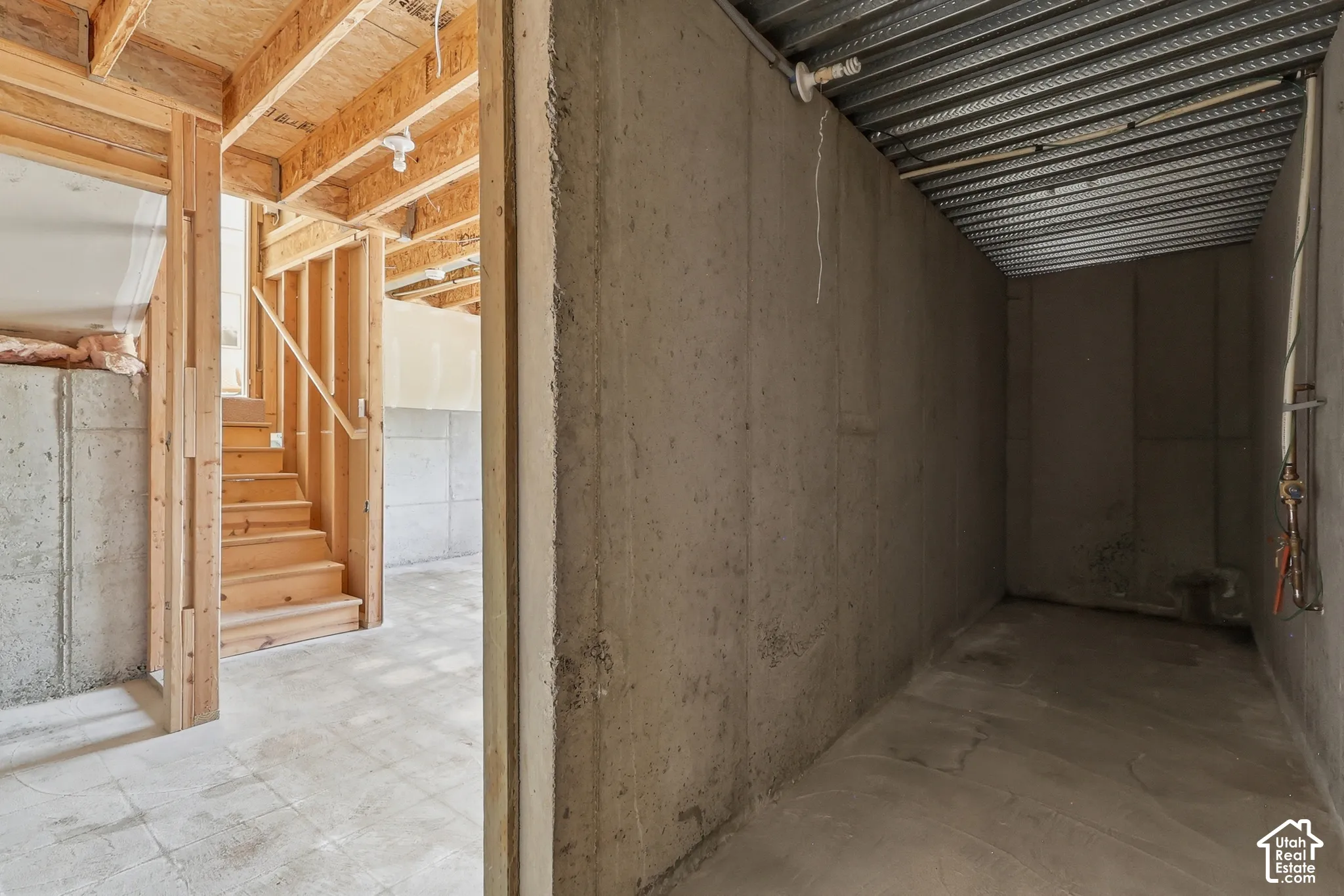 Unfinished basement with concrete flooring, wood framing, and exposed ceiling joists