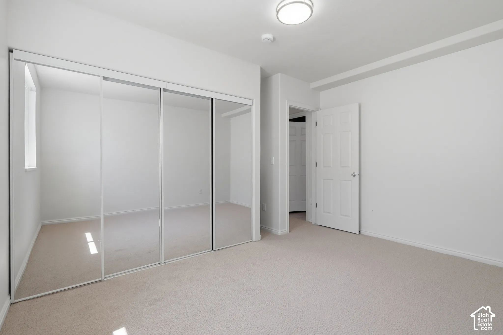Neutral tone carpet flooring, white walls, and a contemporary flush mount light fixture