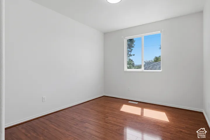 White painted walls, wood-finish flooring, and a window with white trim