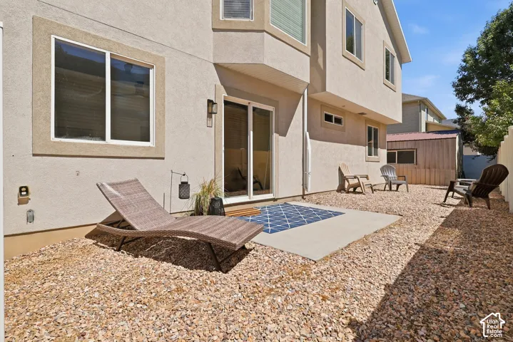 Stucco exterior with multiple windows, concrete patio, and a gravel-covered yard