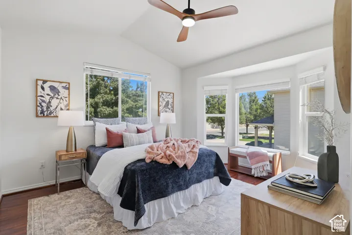 Vaulted ceiling with a wood-finish ceiling fan, wood-finish flooring, and a bay window