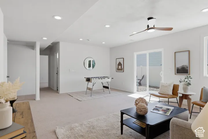 Recessed lighting, ceiling fan with wood-finish blades, sliding glass patio door, light-colored carpet, and white wall finishes