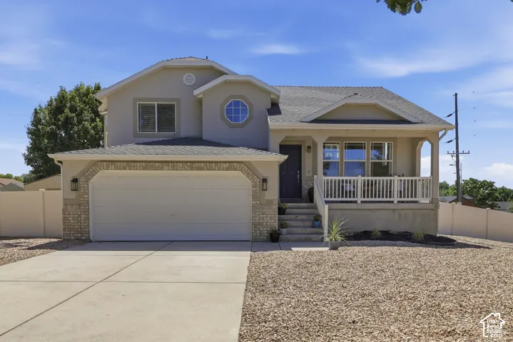 Two-story exterior with a covered porch, attached garage, stone accents, and an octagonal window