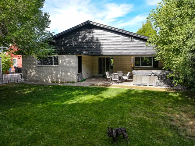 Expansive green lawn with a covered patio area, brick exterior, and dark horizontal siding