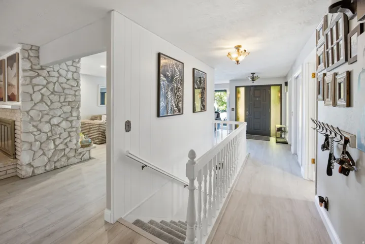 Foyer with wood-finish flooring, white paneled walls, and a stone-clad fireplace surround