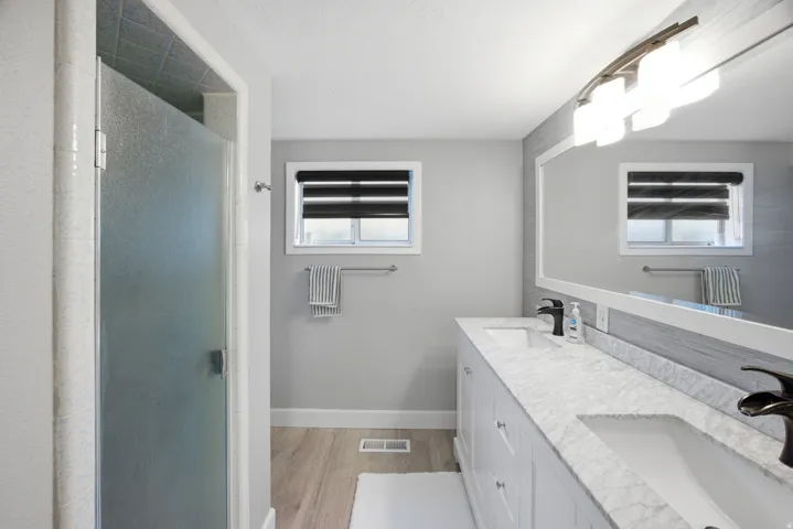 Dual vanity with white cabinetry and integrated sinks, complemented by a large framed mirror and contemporary light fixture