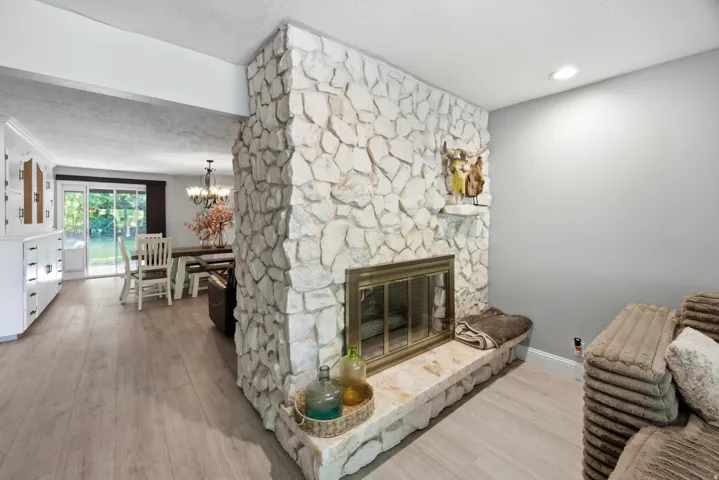 Stone fireplace with a brass firebox, built-in hearth, and mantel shelf