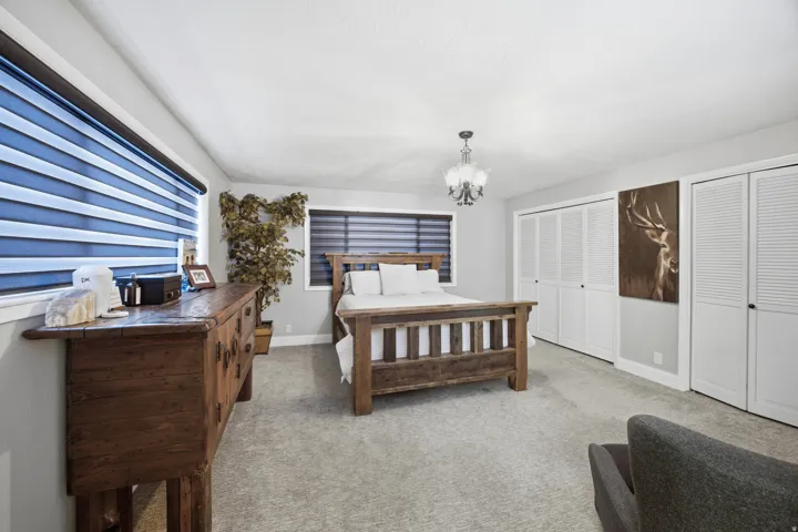 Carpeted flooring, recessed lighting, chandelier light fixture, and multiple windows with horizontal blinds