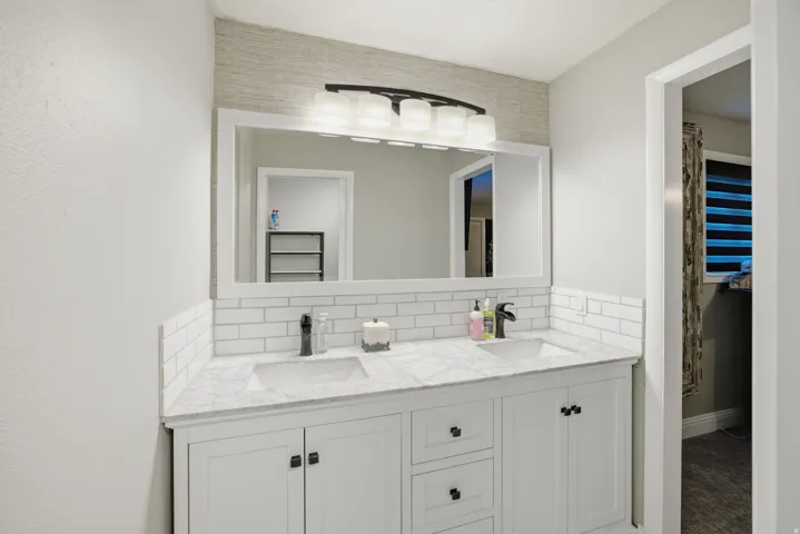 Dual vanity with white shaker-style cabinetry, white countertops, and subway tile backsplash