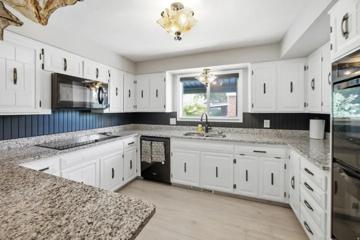 Well-appointed kitchen featuring white cabinetry, light-toned wood-finish flooring, and speckled countertops