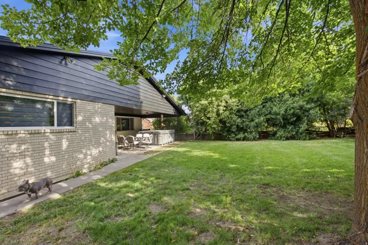 Expansive grassy area featuring mature trees and established perimeter landscaping