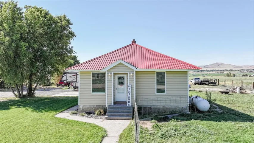 Single-story residence featuring light-colored siding, a vibrant red metal roof, and a white front entry door