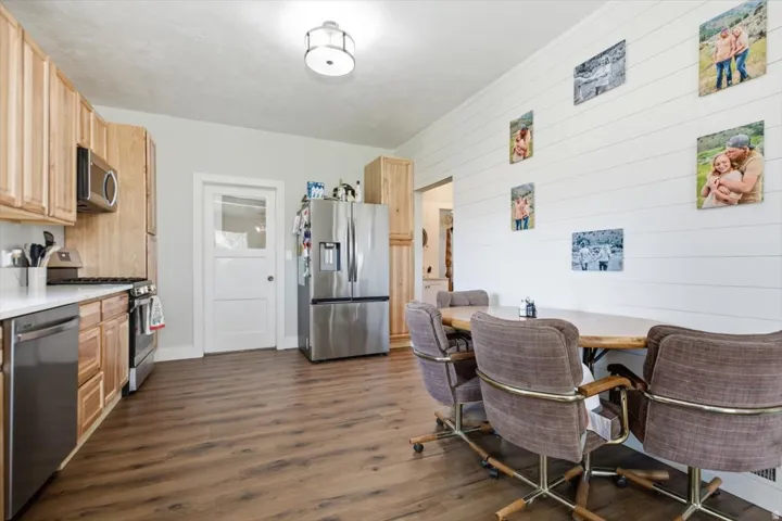 Kitchen featuring wood-finish flooring, light wood cabinetry, stainless steel appliances, and white countertops