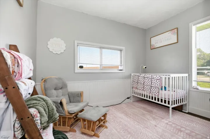 Crisp white baseboards with beadboard paneling, light gray wall paint, and multiple windows with white trim