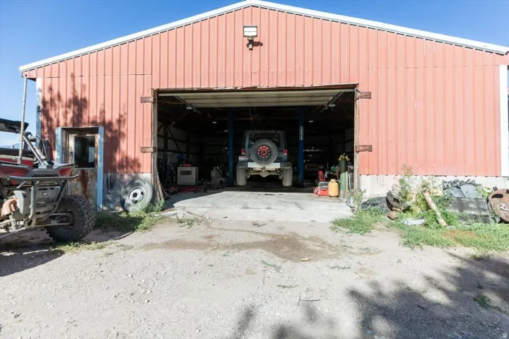 Red corrugated metal building with a large open bay door and a concrete floor