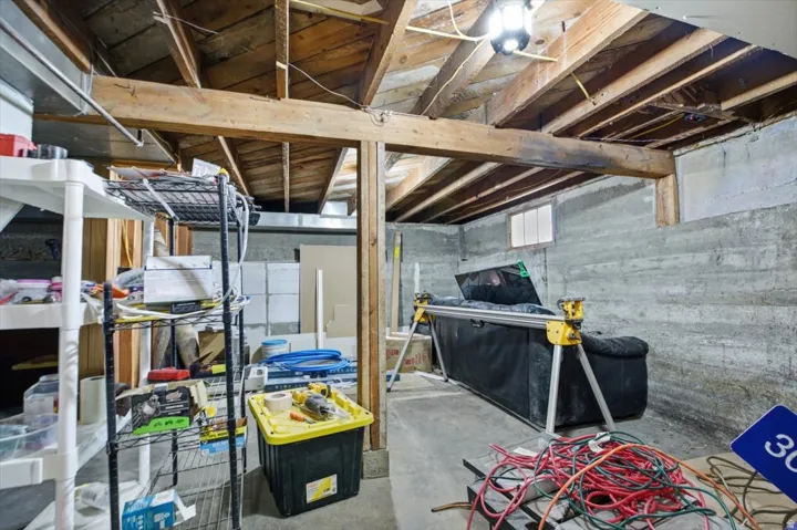 Exposed wood beam ceiling, concrete foundation walls, small transom window, overhead light fixture