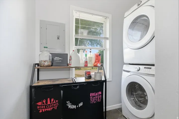 Stackable washer and dryer appliances, window with blinds, and light-colored walls