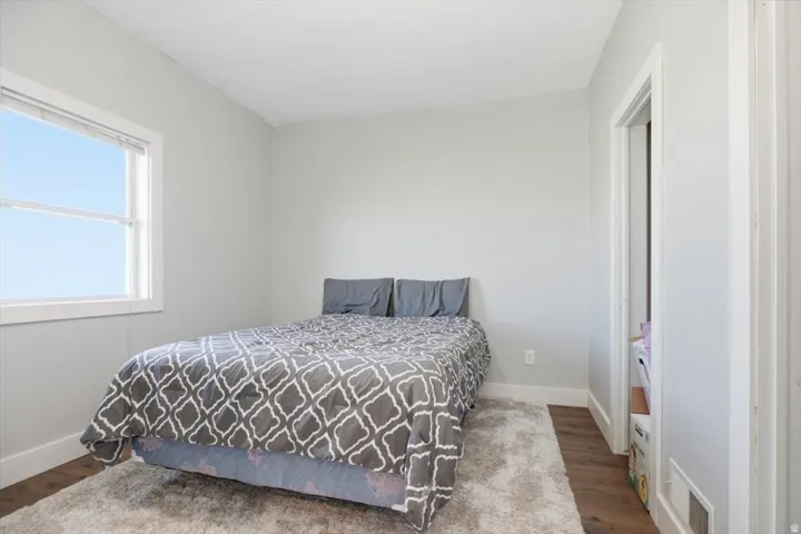White window trim, light gray painted walls, wood-finish flooring, white door frame, and white baseboards