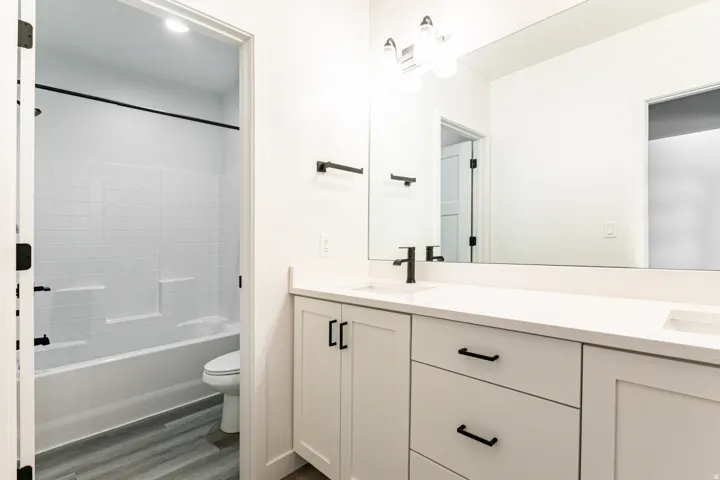 Dual vanity with integrated sinks, white cabinetry, and matte black hardware