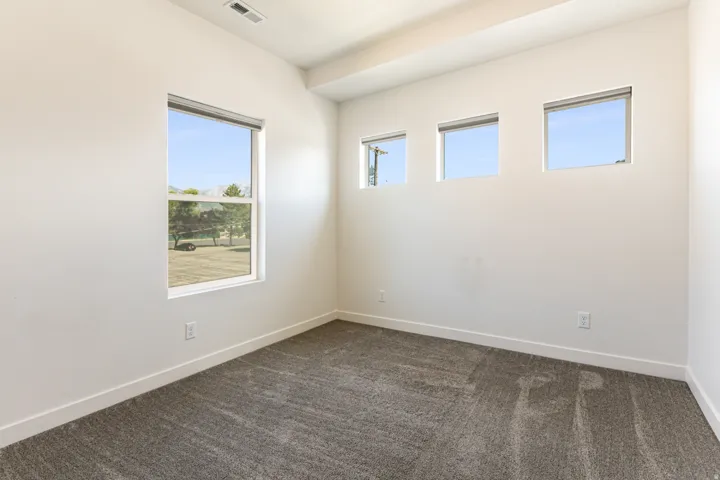 Neutral wall finishes, contemporary window treatments, textured carpeting, and bright overhead lighting
