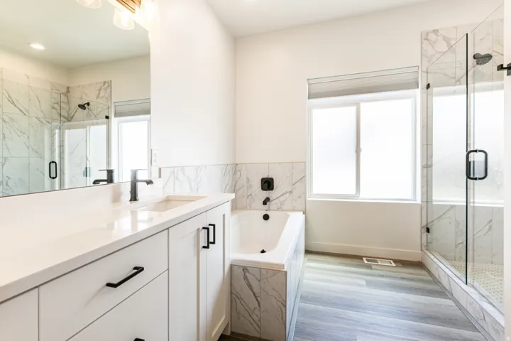 White vanity with a single basin, black faucet, and black pulls