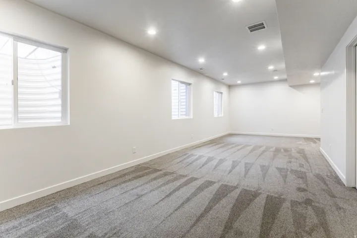 Spacious room featuring neutral paint, recessed lighting, multiple windows, and patterned carpeting