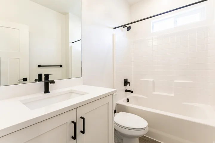 White vanity with a solid surface countertop, integrated rectangular sink, and matte black faucet