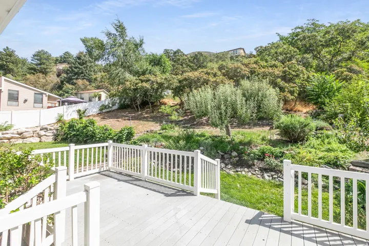 Deck with white railings and an expansive green hillside