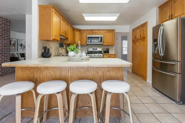 Kitchen featuring wood cabinetry, stainless steel appliances, a breakfast bar, and tile flooring
