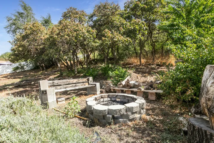 Stone-block fire pit with surrounding seating and mature trees