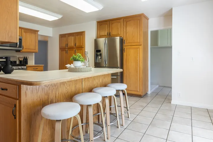 Kitchen featuring wood cabinetry, stainless steel appliances, a breakfast bar, and tiled flooring