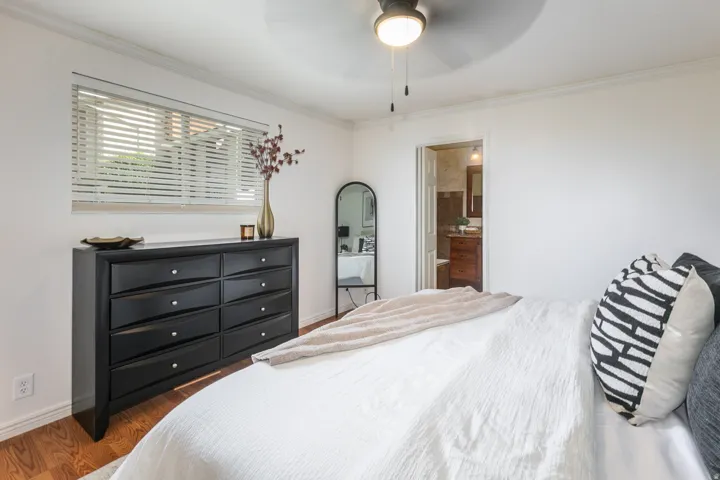 Recessed window with blinds, wood-finish flooring, ceiling fan with light fixture, and crown molding