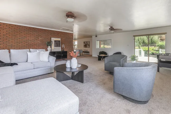 Expansive living area with brick accent wall and carpet flooring