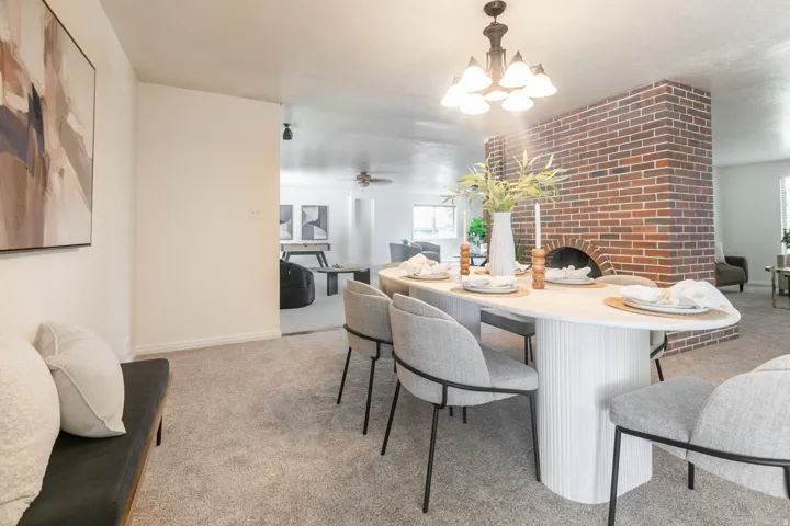 Open-concept layout with light-toned carpet flooring and a prominent brick fireplace