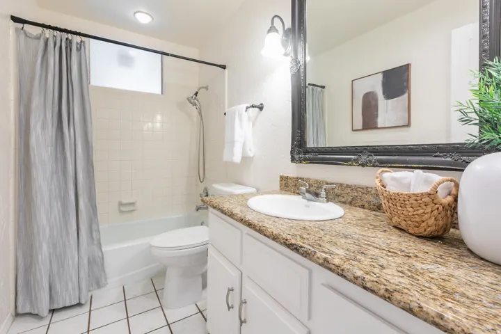 Vanity with a granite-style countertop, undermount sink, and white cabinetry