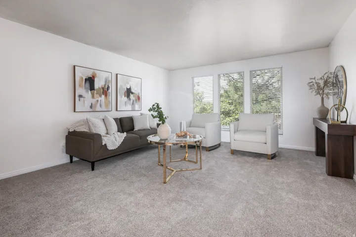 Bright living area featuring abundant natural light, light-toned carpeting, and multiple windows