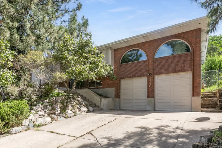 Brick facade with two arched windows, two garage doors, and a concrete driveway