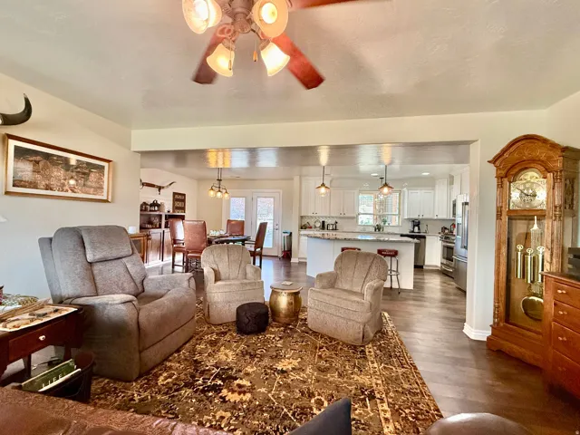 Expansive living area featuring wood-finish flooring, a ceiling fan with integrated lighting, and an open concept layout